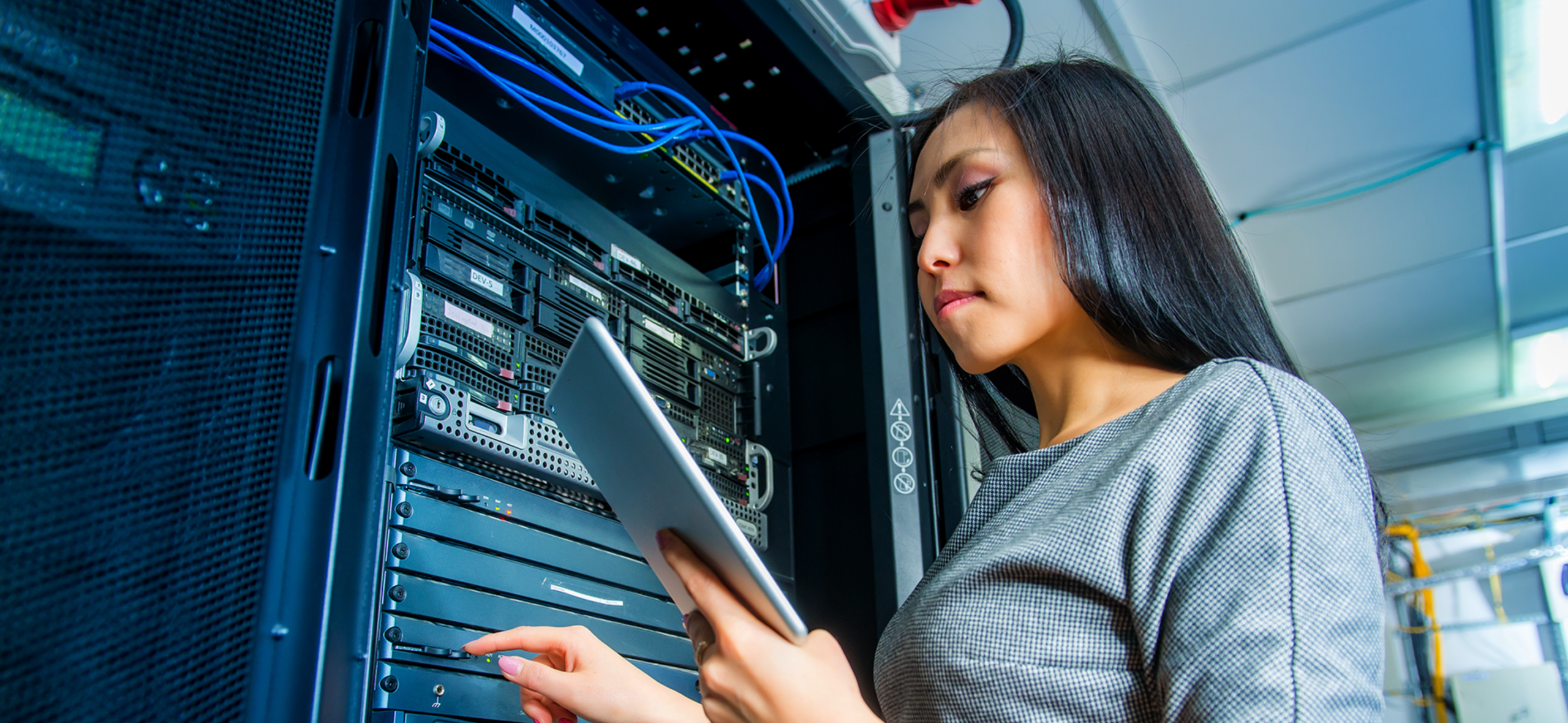 Engineer looking at tablet in server room