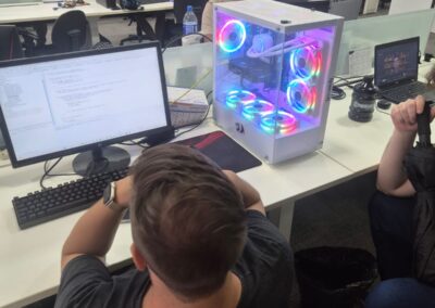 Workers sit at computers with neon-lit new-age looking CPU on desk.